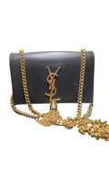 Black  YSL clutch bag with gold chain and Yves Saint Laurent logo on a wooden surface.