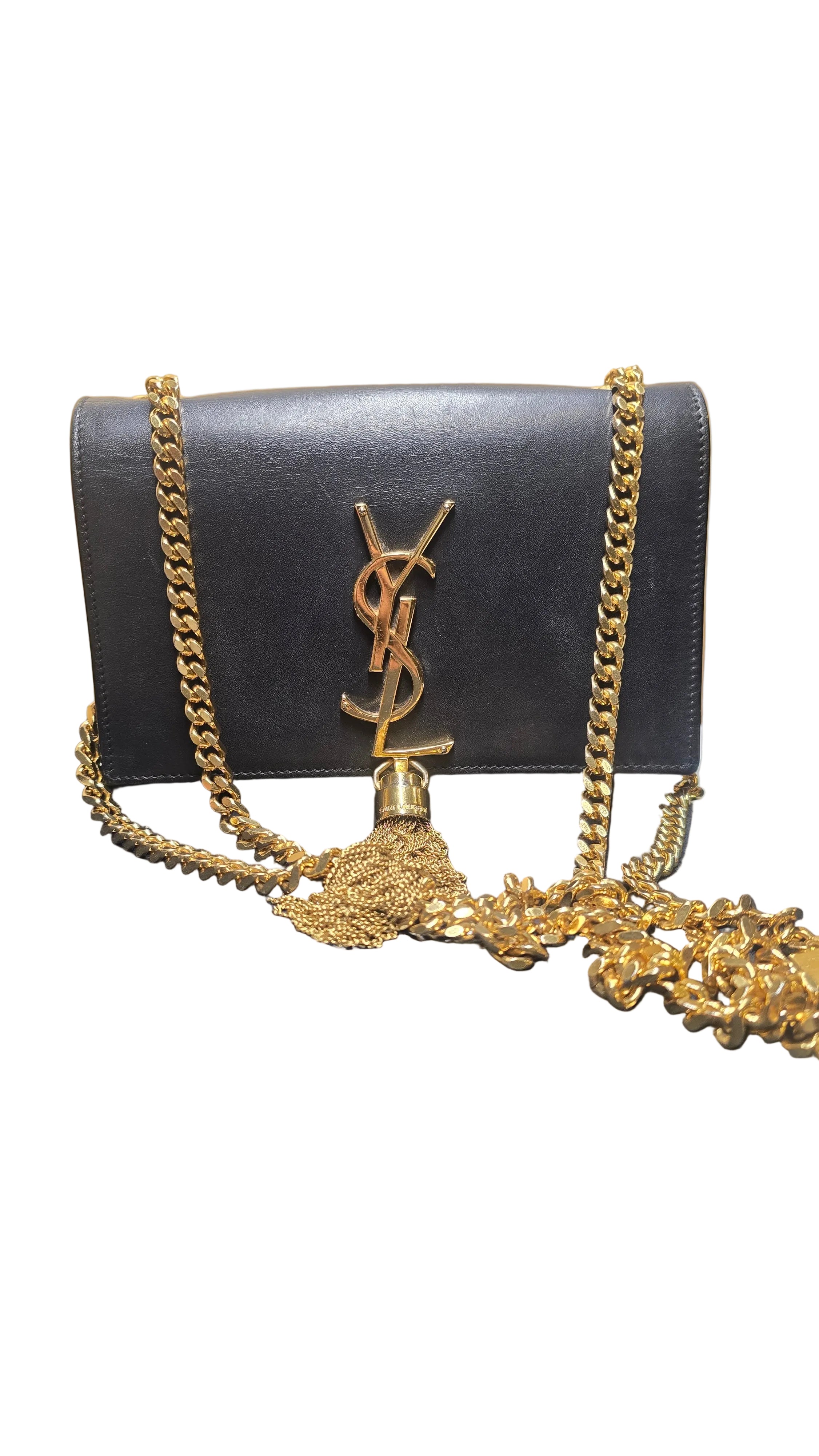 Black  YSL clutch bag with gold chain and Yves Saint Laurent logo on a wooden surface.